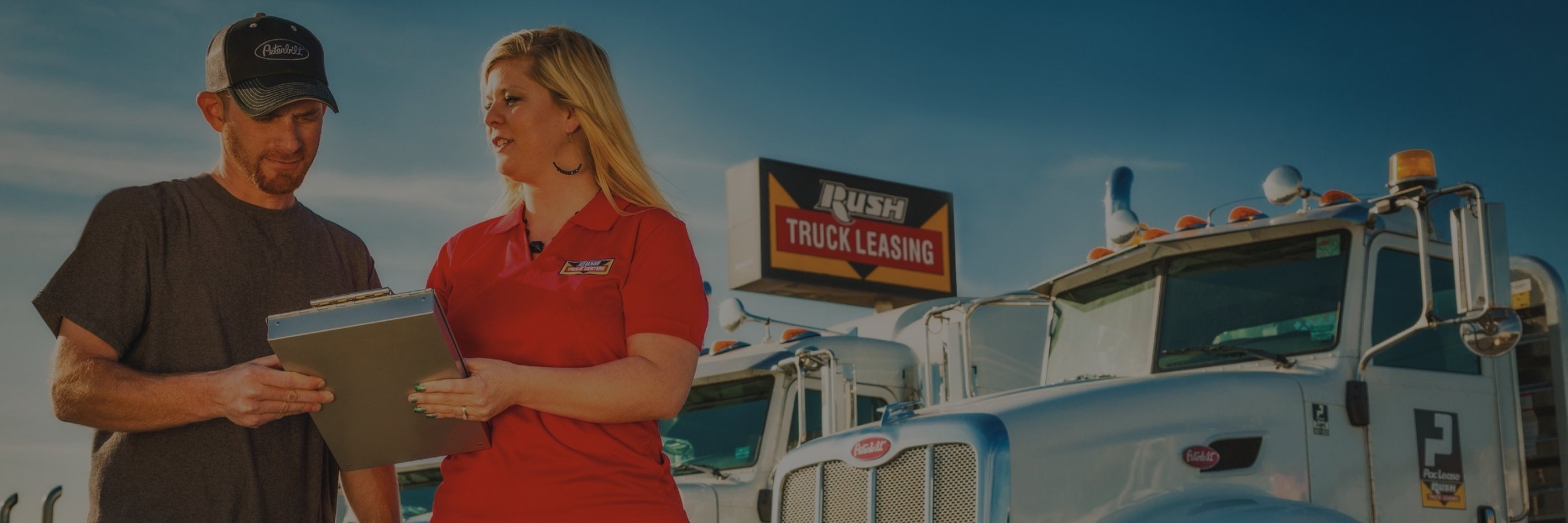 Rush Truck Leasing employee with customer in front of trucks and store sign